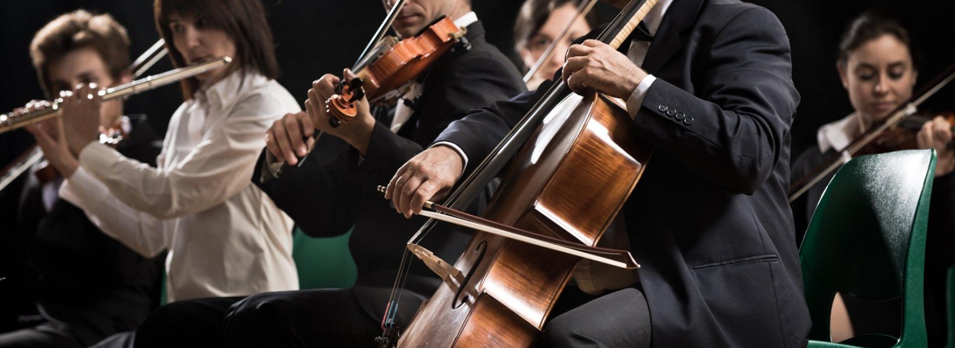 Ausschnitt eines Orchesters. Darauf zu sehen drei Personen, die live spielen.